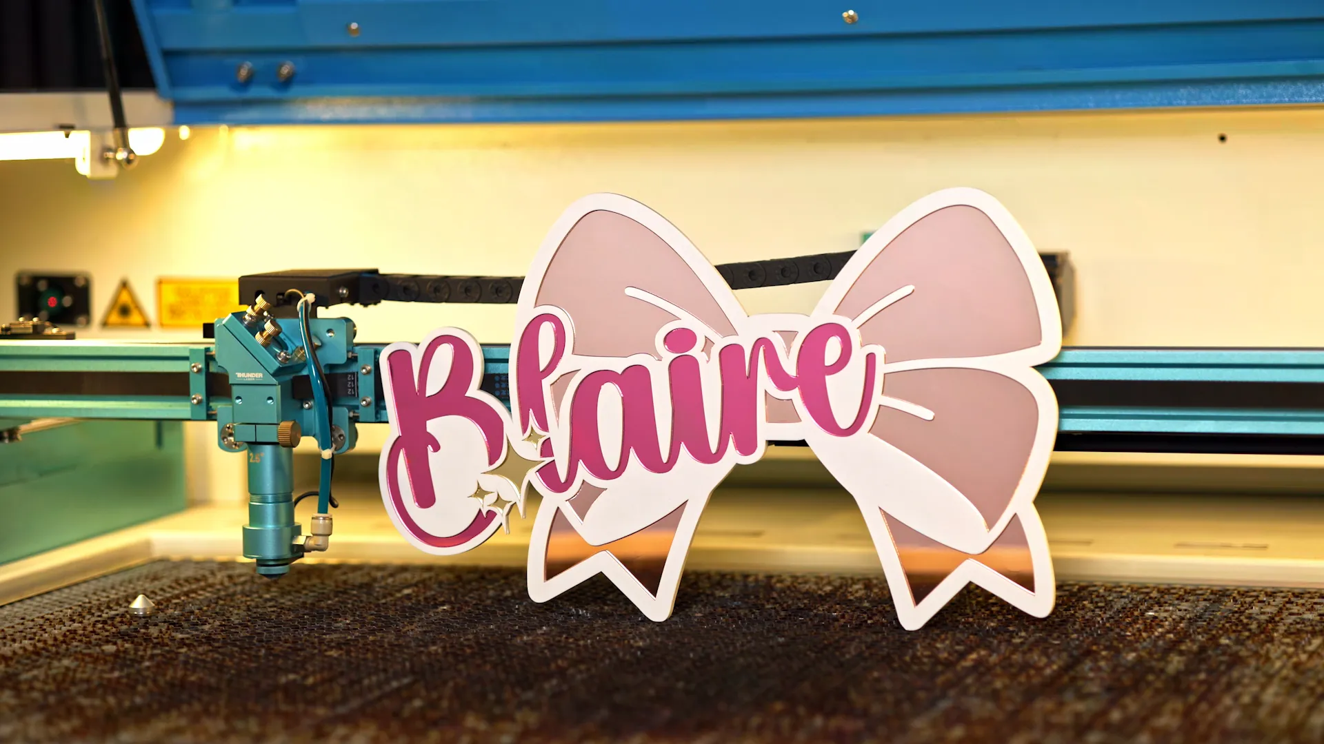 Finished layered laser cut acrylic sign with pink name lettering and bow design
