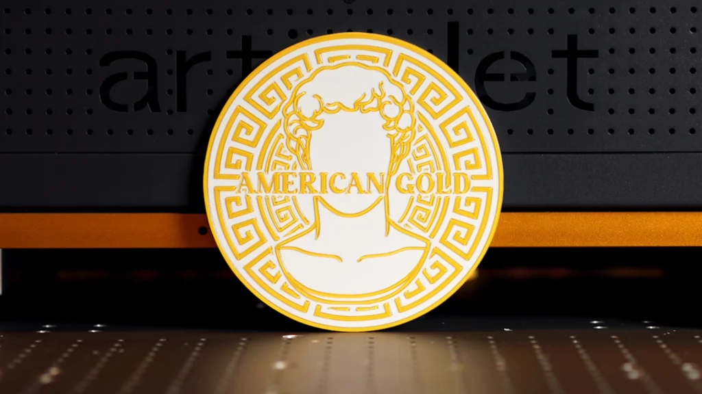 Finished American gold UV print with raised varnish detail displayed in front of an ArtisJet UV printer.