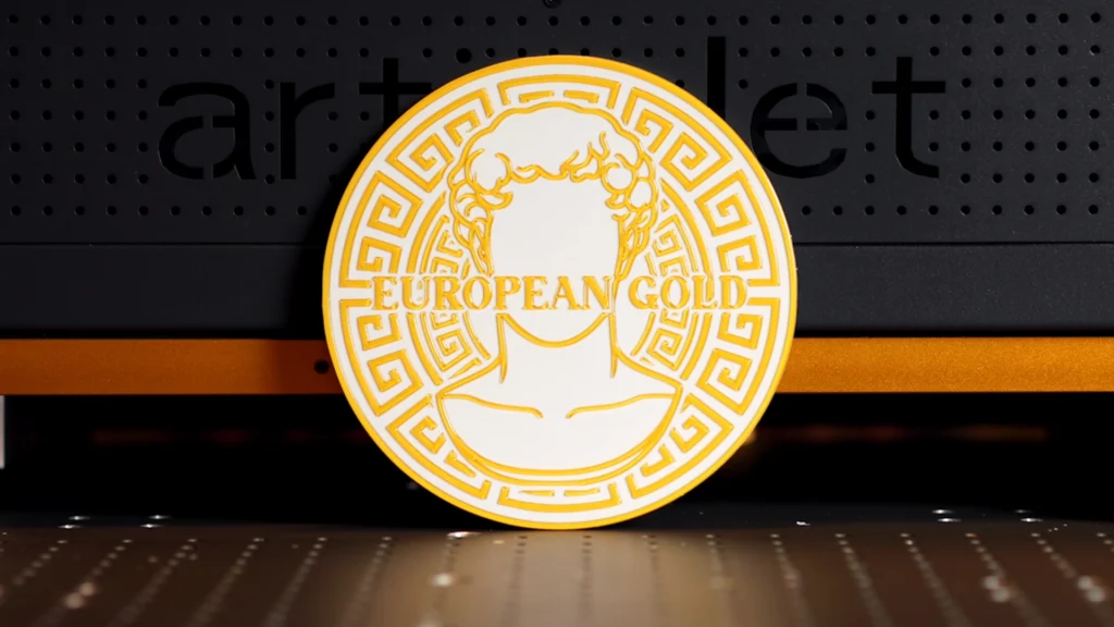 Finished European gold UV print with raised varnish detail displayed in front of an ArtisJet UV printer.