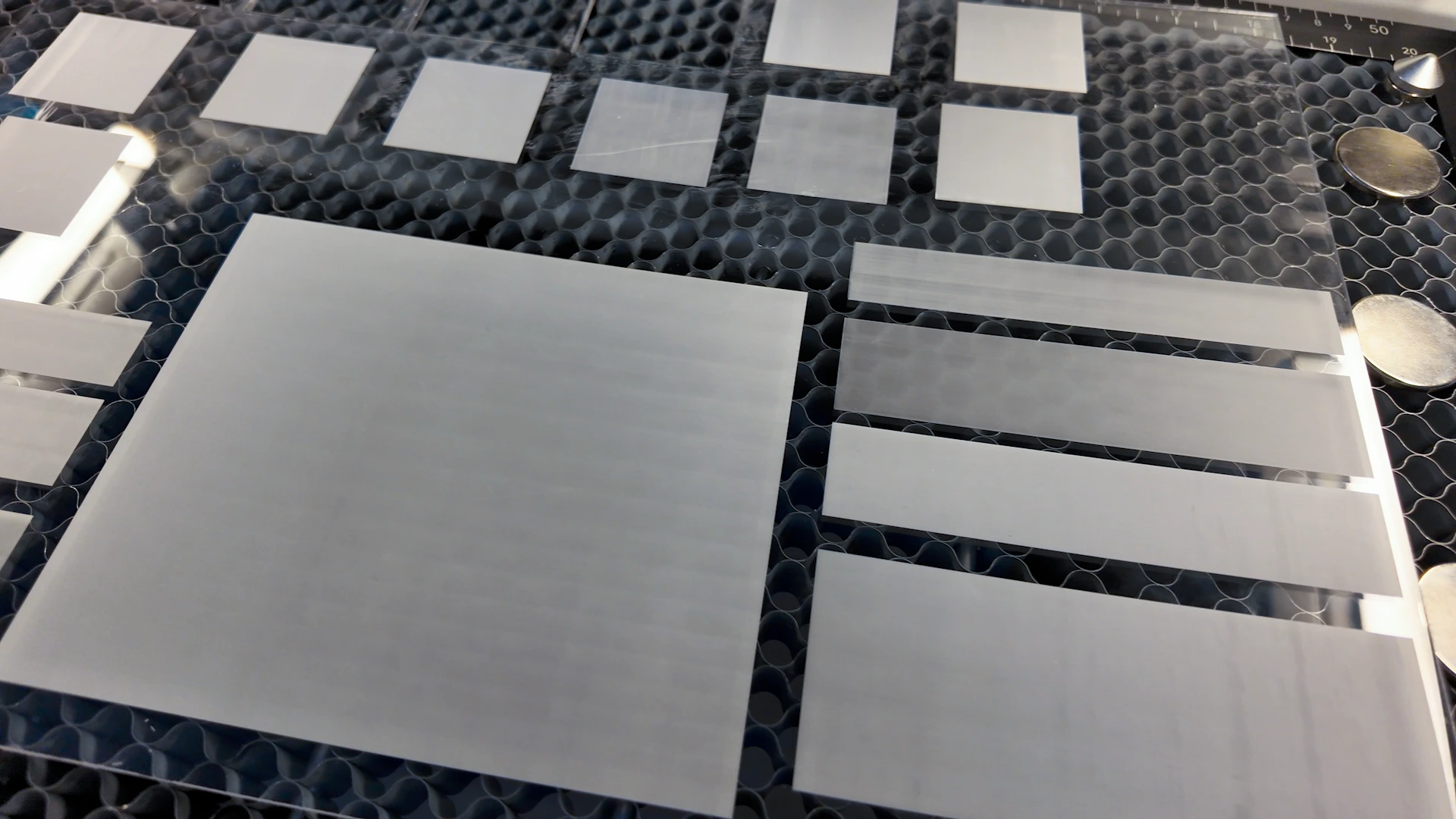 Clear acrylic sheet with frosted test blocks comparing engraving settings and scan line visibility