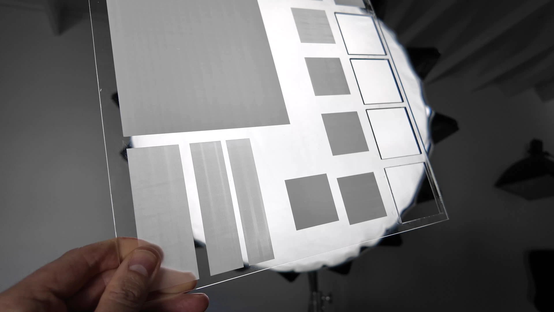 Clear acrylic sheet with engraved test blocks comparing frosting, scan lines and outline settings
