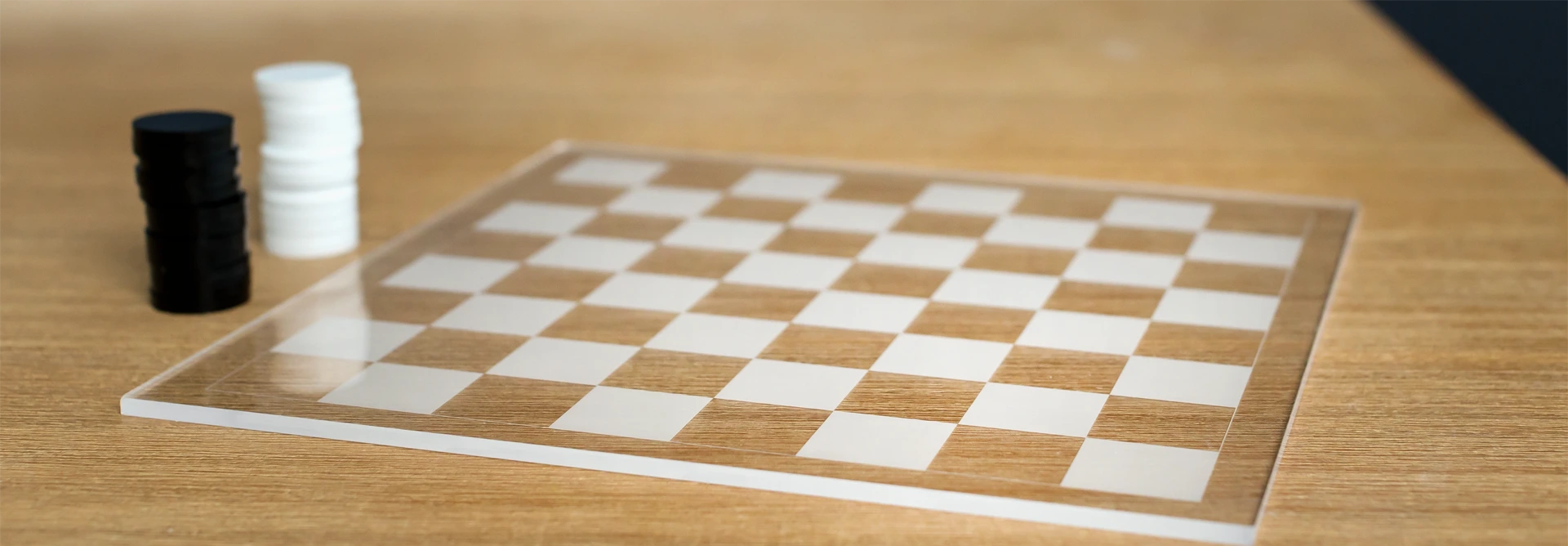 Finished clear acrylic checkers board with frosted squares and stacked black and white pieces