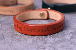 Red leather bracelet engraved with motivational text around the outer band.