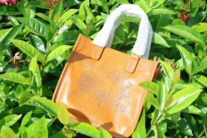 Tan leather handbag engraved with a floral design and personalised text.