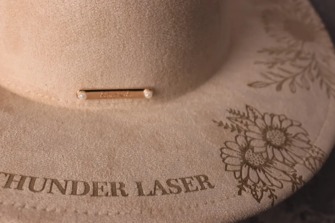 Leather hat engraved with floral artwork and text.