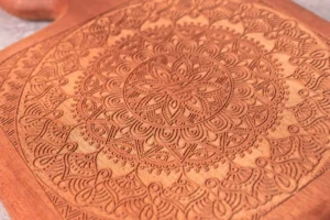 Close-up of leather engraved with an intricate circular mandala pattern.