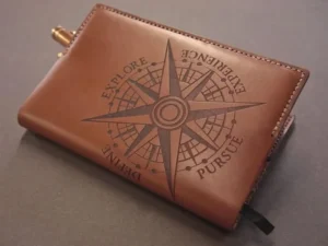 Brown leather wallet engraved with a detailed compass design and surrounding text.