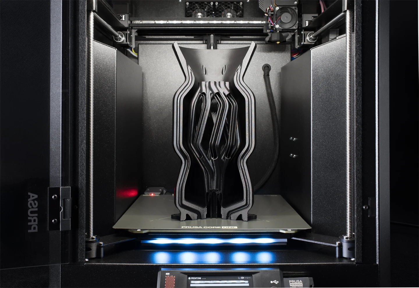 rusa enclosed FDM 3D printer building a large part layer by layer from thermoplastic filament.