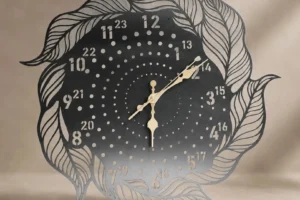 Decorative laser-cut metal wall clock featuring an intricate leaf design, numbered face and gold hands.
